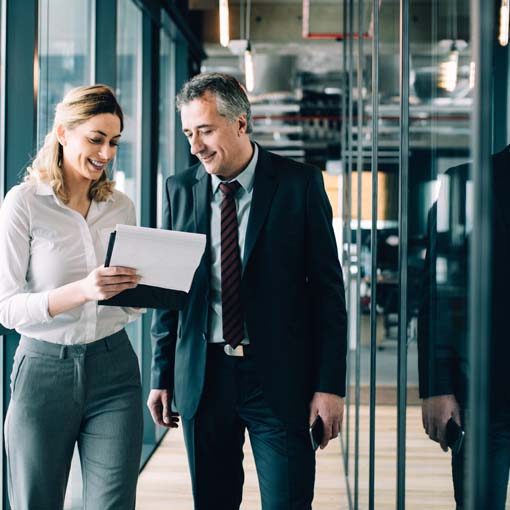 Colleagues walking down a corridor discussing a report.