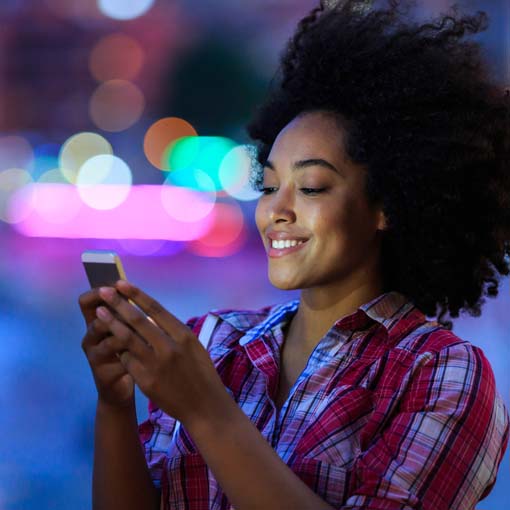 Woman checking smartphone in street at night.