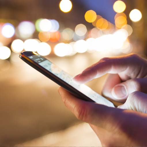 Person using smartphone in the street at night.