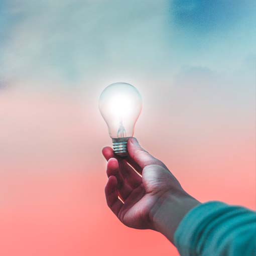 A hand holding a lit lightbulb