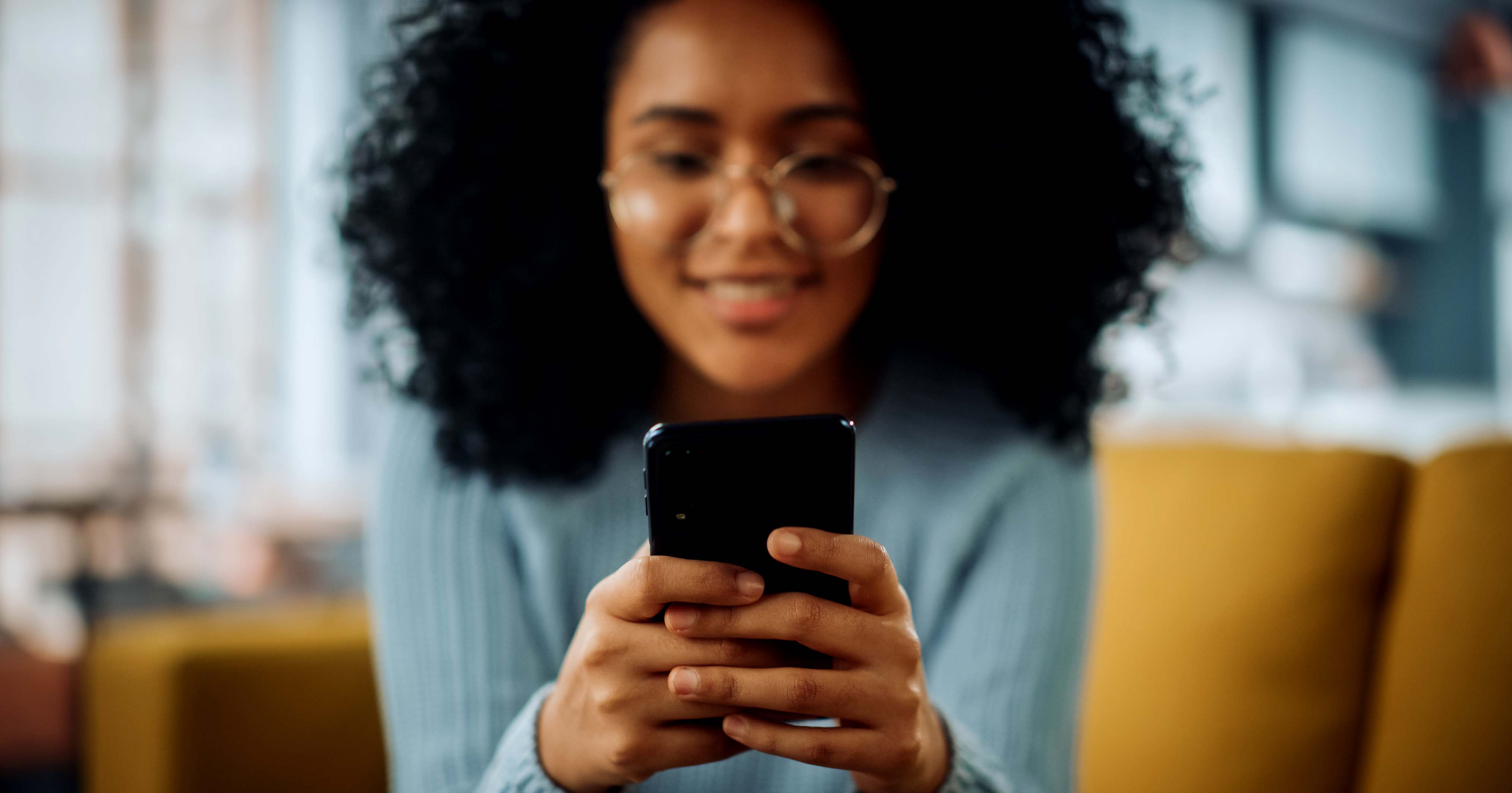 An image of a woman relaxing at home whilst using a smartphone.